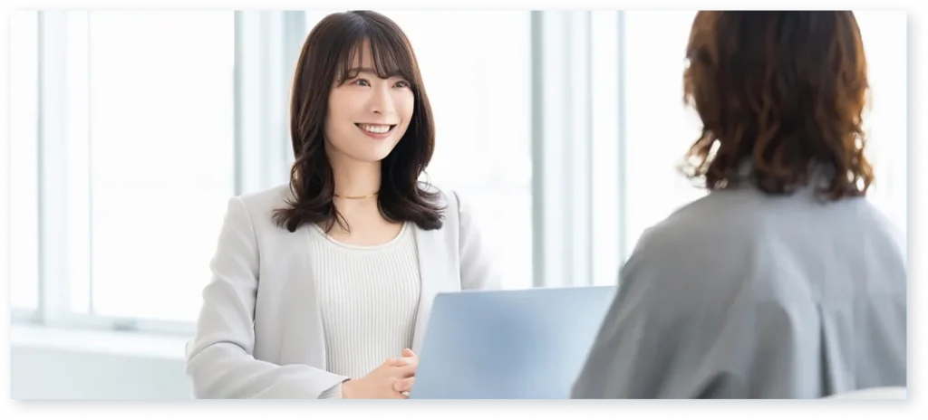 オフィスでノートパソコンを見ながら会話する2人の女性