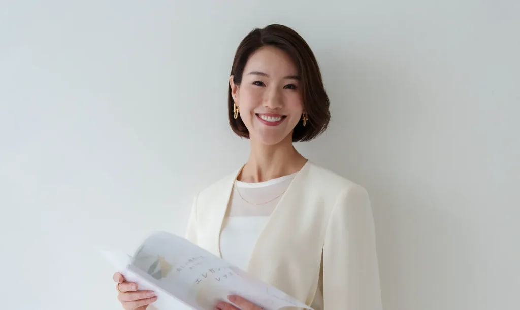 冊子を手に微笑む女性のポートレート写真